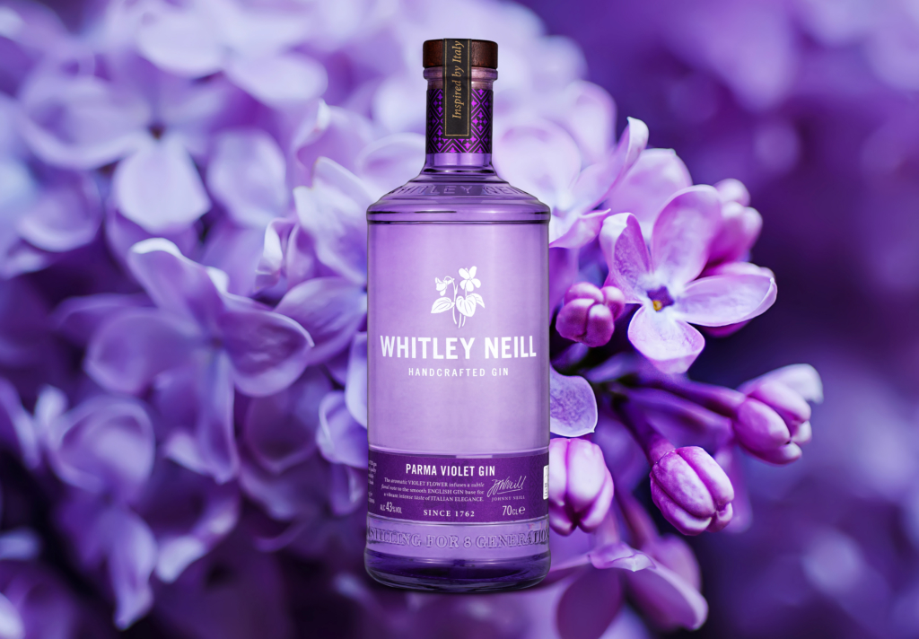 Billede af en flaske Parma Violet gin fra Whitley Neill med Violet blomster i baggrunden